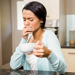 woman covering mouth and holding coffee cup