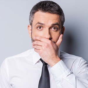 man in business attire covering mouth